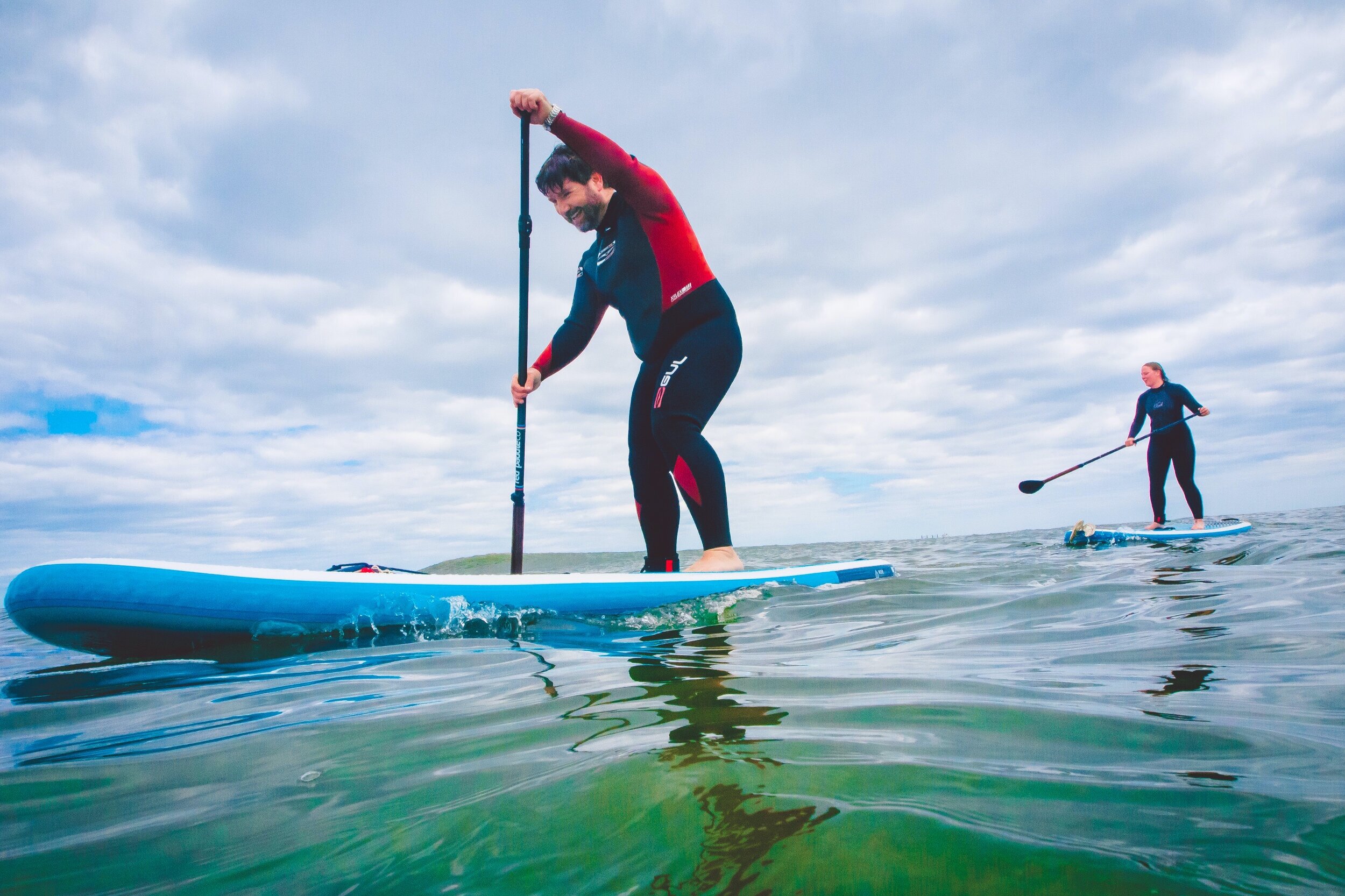 Man and woman paddleboarding in North Sea